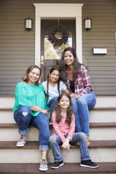 Female Multi Generation Family Sit On Steps in Front Of House