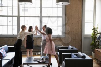 Female colleagues high five at a motivational meeting