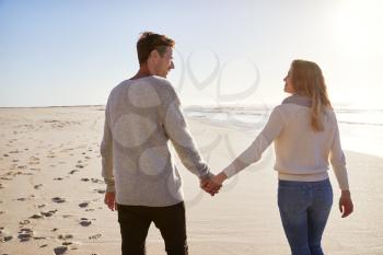 Rear View Of Loving Couple Walking Along Winter Beach Together