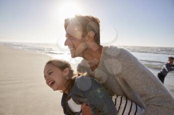 Father With Daughter Having Fun On Winter Beach Together