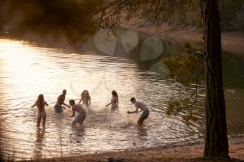 Young adult friends splashing and having fun in a lake