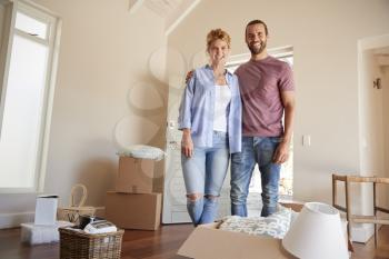 Portrait Of Couple Surrounded By Boxes In New Home On Moving Day