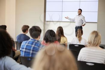 Teacher Giving Presentation To High School Class In Front Of Screen