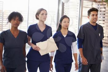 Healthcare workers walking through hospital with patient notes