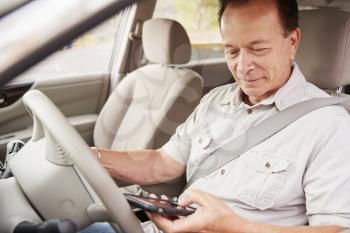 Senior man in car using his smartphone while driving