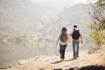 Senior couple hiking by a mountain lake, back view