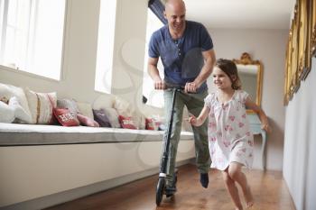 Dad on scooter following as  daughter runs through the house
