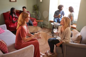 Two female friends talking and having a drink in a pub