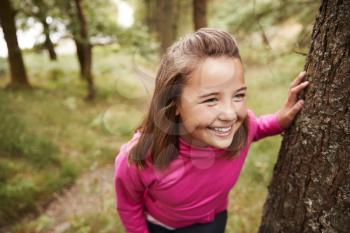 Pre-teen girl taking a break leaning on tree during a hike in a forest, elevated view, close up