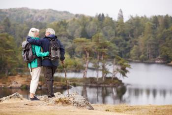 Senior couple embracing and admiring a view of lakes looking at each other, back view