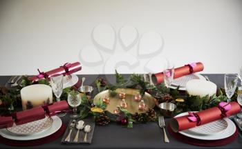 Decorated Christmas table set for four people, with Christmas crackers arranged on plates