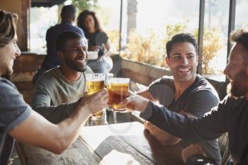 Group Of Male Friends Meeting In Sports Bar Making Toast Together