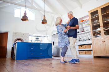 Senior Couple At Home Dancing In Kitchen Together