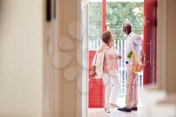 Mature Couple Returning Home From Shopping Trip Carrying Grocery Bags