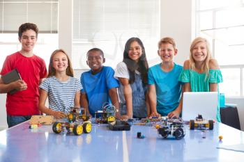 Portrait Of Male And Female Students Building Robot Vehicle In After School Computer Coding Class