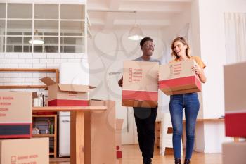 Smiling Couple Carrying Boxes Into New Home On Moving Day