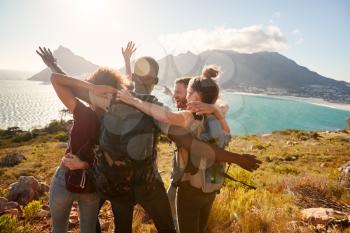Young adult friends on a hike celebrate reaching a summit near the coast together