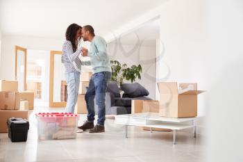 Loving Couple Surrounded By Boxes In New Home On Moving Day