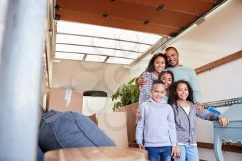 Portrait Of Family Standing On Tailgate Of Removal Truck Outside New Home