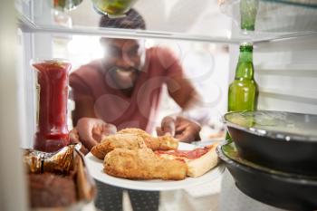 View Looking Out From Inside Of Refrigerator Filled With Unhealthy Takeaway Food As Man Opens Door