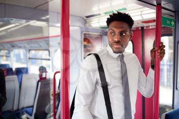 Businessman Standing In Train Commuting To Work