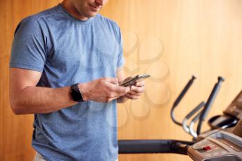 Close Up Of Man Exercising On Treadmill At Home Wearing Smart Watch Checking Mobile Phone