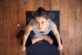 Overhead Portrait Of Woman Sitting On Exercise Mat Wearing Wireless Earphones Connected To Phone