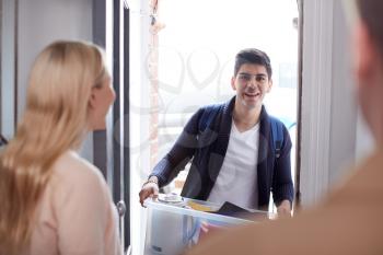 Male College Student Carrying Box Moving Into Accommodation Meeting House Mates