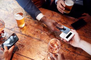 Close Up Of Businessman Paying For Round Of Drinks In Bar After Work Using Contactless Card