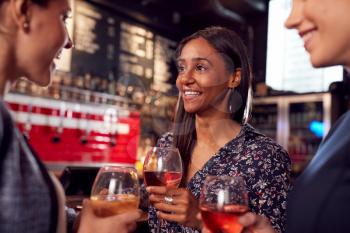 Three Women Meeting For Drinks And Socializing In Bar After Work