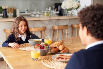 Children Wearing Uniform In Kitchen Eating Breakfast Before Going To School