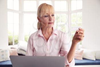 Mature Woman At Home Looking Up Information About Medication Online Using Laptop