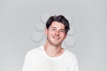 Studio Portrait Of Young Man Wearing White T Shirt Smiling At Camera
