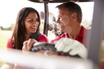 Mature Couple Playing Golf Driving Buggy Along Course To Green On Red Letter Day