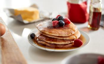 Stack Of Freshly Made Pancakes Or Crepes With Maple Syrup And Berries On Table For Pancake Day
