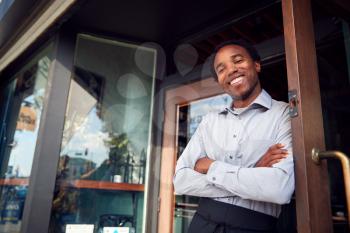 Portrait Of Male Owner Of Start Up Coffee Shop Or Restaurant Standing In Doorway