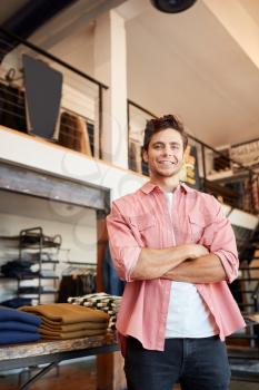 Portrait Of Smiling Male Owner Of Fashion Store Standing In Front Of Clothing Display