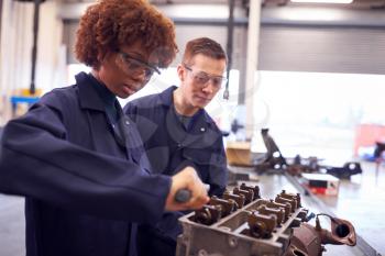 Male And Female Students Work On Car Engine Block On Auto Mechanic Apprenticeship Course At College