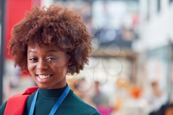 Portrait Of Smiling Female College Student In Busy Communal Campus Building