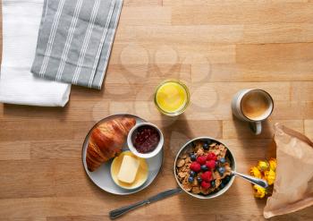 Overhead Flat Lay Shot Of Table Laid For Breakfast With Cereal Croissant And Flowers