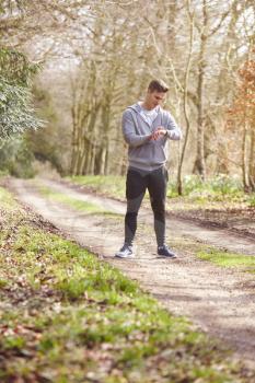 Man Running In Countryside Exercising Checking Smart Watch Fitness Activity App