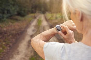 Close Up Of Senior Woman Running In Countryside Exercising Checking Smart Watch Fitness Activity App
