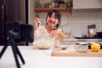 Asian Girl Baking Cupcakes In Kitchen At Home Whilst On Vlogging On Mobile Phone