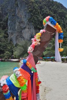 The native boat decorated with silk tapes is moored in thin gentle beach sand. Island Phi-Phi, Thailand
