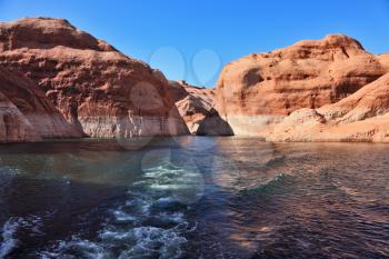  Lakeside in red sandstone covered sunset. Boat trip on the picturesque Lake Powell.
