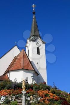 Church built on a hill and surrounded by flowers.  Church clearly look elegant against the clear blue sky