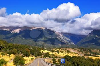  The road the Ruta 40 passes in Argentina among fields. Magnificent cumulus clouds decorate mountains of the Southern Andes