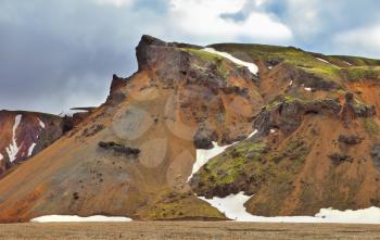 Rhyolite mountains. Colorful smooth mountains in the Icelandic reserve Landmannalaugar. In the hollows is last year's snow