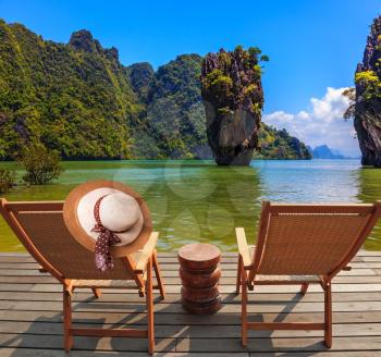 Exotic rest in Thailand. The coast of the gulf in the Andaman Sea. Two chaise lounges and an elegant hat on one