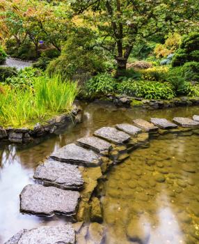   The track of stones in  water in Japanese part of garden. Decorative private garden on Vancouver Island in Canada - Butchart Gardens